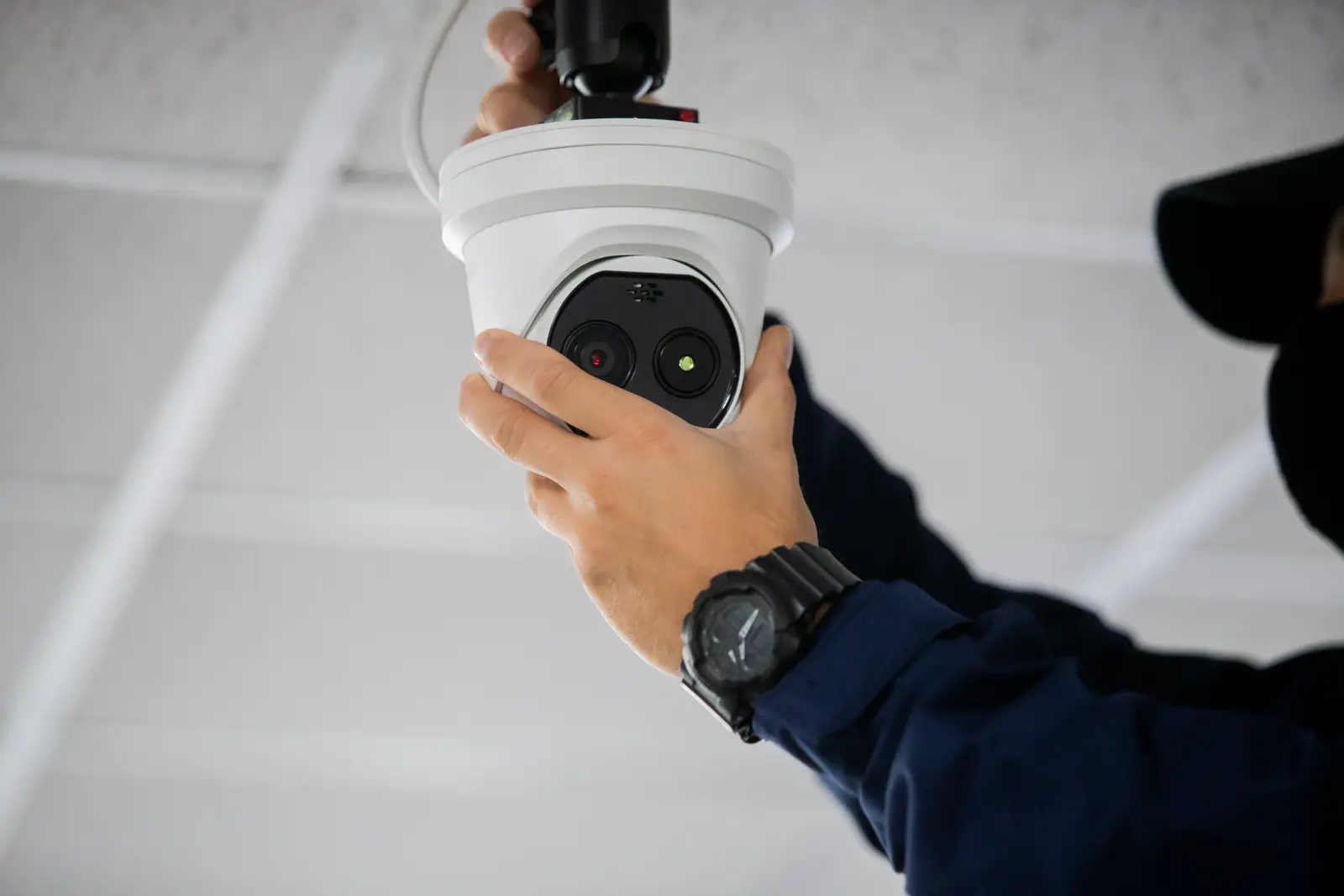 Technicien certifié testant un détecteur de fumée au plafond d'un bureau avec un équipement de contrôle spécialisé